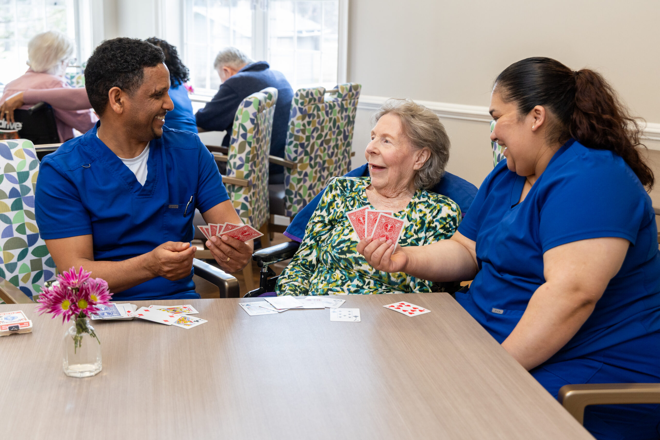 Arbor Place caregivers playing cards with residents, highest staffing ratios in memory care Rockville, MD | Alzheimer's Specialists in Rockville MD